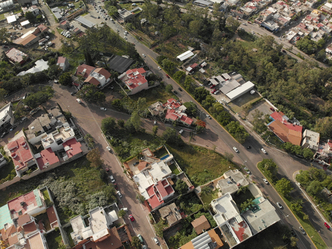 Aerial view of residential houses with red tiled roofs tree lined streets and vehicles driving along roads in Tlaquepaque Jalisco Mexico. Aerial view of residential houses with red tiled roofs tree lined streets and vehicles driving along roads in Tlaquepaque Jalisco Mexico.