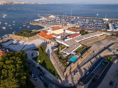 Aerial view of Cidadela de Cascais featuring historic stone fortifications a swimming pool and a marina filled with boats along the Atlantic coast in Cascais Lisboa Portugal. Aerial view of Cidadela de Cascais featuring historic stone fortifications a swimming pool and a marina filled with boats along the Atlantic coast in Cascais Lisboa Portugal.