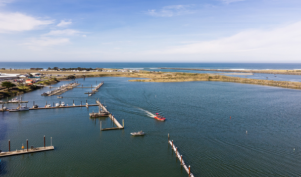Gold Beach United States 23 September 2026 Aerial view of Jerry s Rogue Jets boats in the marina at the mouth of the Rogue River with docks and the Pacific Ocean in the background.