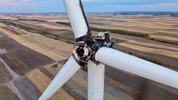 Aerial view of a damaged wind turbine with charred blades and hub after a fire set against a vast landscape of agricultural fields in Vladimirovac Vojvodina Serbia.