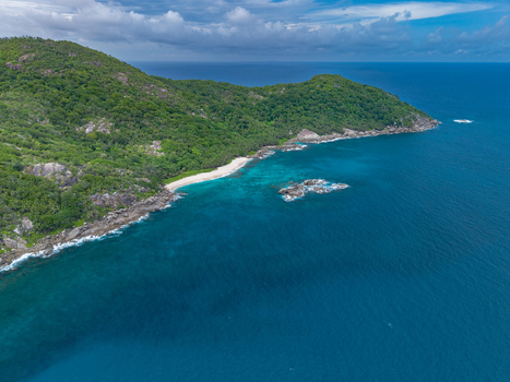 Aerial view of the lush green island meeting the turquoise sea with white sand beaches and rocky outcrops Mahe Island Seychelles. Aerial view of the lush green island meeting the turquoise sea with white sand beaches and rocky outcrops Mahe Island Seychelles.