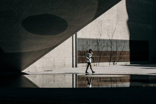 Zurich Switzerland 02 April 2023 View of a solitary figure strides past the National Museum its stark concrete contrasting with the water reflection. Zurich Switzerland 02 April 2023 View of a solitary figure strides past the National Museum its stark concrete contrasting with the water reflection.