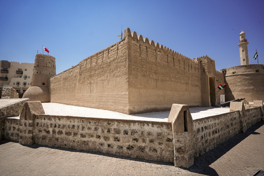 View of the historic Al Fahidi Fort with its traditional stone walls defensive towers and a minaret under a clear blue sky in Dubai Dubai United Arab Emirates. View of the historic Al Fahidi Fort with its traditional stone walls defensive towers and a minaret under a clear blue sky in Dubai Dubai United Arab Emirates.