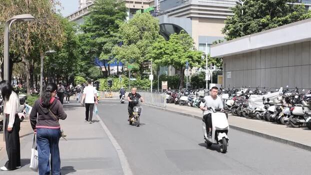 View of people and scooters on a street in Shenzhen China. View of people and scooters on a street in Shenzhen China.