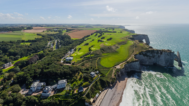 Aerial view of the dramatic cliffs meeting the turquoise sea lush green golf courses contrasting with the white chalk formations &Eacute;tretat Normandy France.