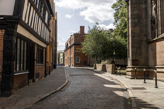 View of a narrow cobblestone street in the historic center of Coventry featuring timber framed buildings and red brick architecture Coventry England United Kingdom.