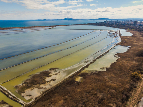 Aerial view of the salt pans of Lake Atanasovsko with the city skyline and Black Sea coast under a cloudy sky in Burgas Burgas Bulgaria. Aerial view of the salt pans of Lake Atanasovsko with the city skyline and Black Sea coast under a cloudy sky in Burgas Burgas Bulgaria.