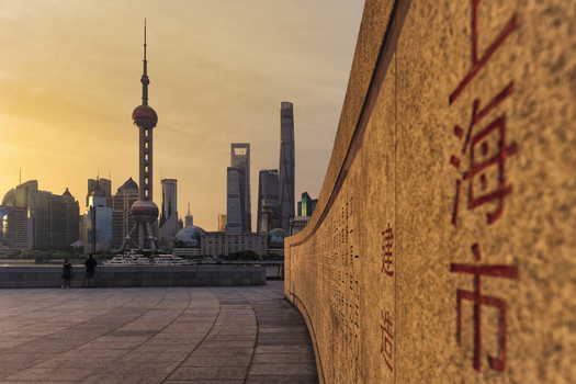 View of the Shanghai skyline featuring the Oriental Pearl Tower and modern skyscrapers at sunset with a stone wall in the foreground in Shanghai Shanghai China. View of the Shanghai skyline featuring the Oriental Pearl Tower and modern skyscrapers at sunset with a stone wall in the foreground in Shanghai Shanghai China.