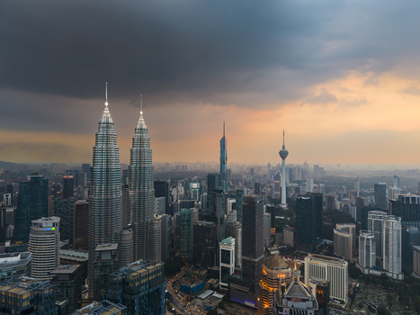Kuala Lumpur Malaysia 11 March 2026 Aerial view of the Petronas Twin Towers and the city skyline under dramatic storm clouds at sunset.