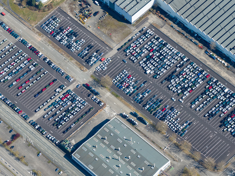 Aerial view of orderly rows of parked cars gleaming under the sun amidst the industrial landscape Sausheim Grand Est France.