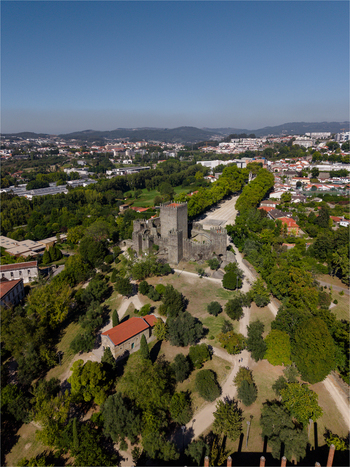 Aerial view of Guimaraes Castle and Igreja de Sao Miguel do Castelo surrounded by lush parkland and the historic urban landscape of Guimaraes Braga Portugal. Aerial view of Guimaraes Castle and Igreja de Sao Miguel do Castelo surrounded by lush parkland and the historic urban landscape of Guimaraes Braga Portugal.