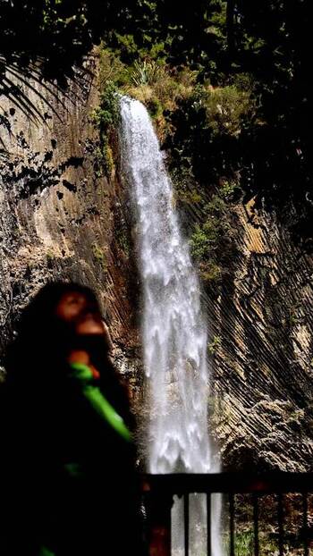 View of a person admiring a powerful waterfall New Zealand.