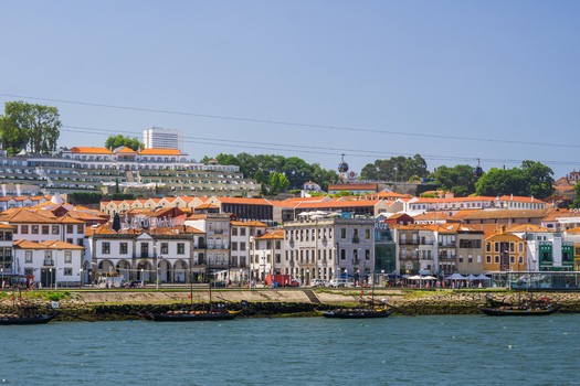 Aerial view of the Douro River reflecting the clear sky contrasting with the warm tones of the Ribeira district s buildings and traditional boats Porto Porto District Portugal. Aerial view of the Douro River reflecting the clear sky contrasting with the warm tones of the Ribeira district s buildings and traditional boats Porto Porto District Portugal.