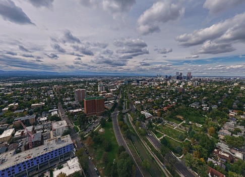 Aerial view of Cherry Creek winding through the urban landscape with the Denver skyline in the background under a cloudy sky in Denver Colorado United States. Aerial view of Cherry Creek winding through the urban landscape with the Denver skyline in the background under a cloudy sky in Denver Colorado United States.