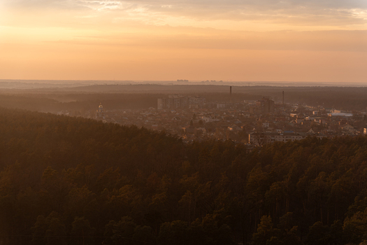 Aerial view of the city nestled amongst the dark green forest under a soft orange sky Kyiv Kyiv city Ukraine. Aerial view of the city nestled amongst the dark green forest under a soft orange sky Kyiv Kyiv city Ukraine.