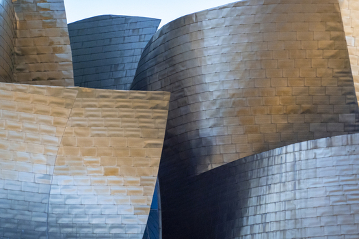 View of the curved titanium panels and metallic facade of the Guggenheim Museum Bilbao in Bilbao Euskadi Spain. View of the curved titanium panels and metallic facade of the Guggenheim Museum Bilbao in Bilbao Euskadi Spain.