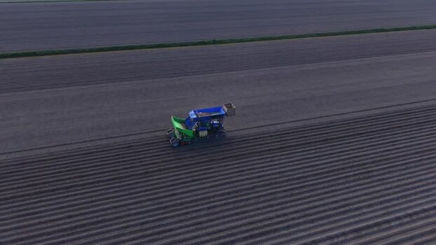 Aerial view of a tractor planting seeds in a furrowed field Netherlands.