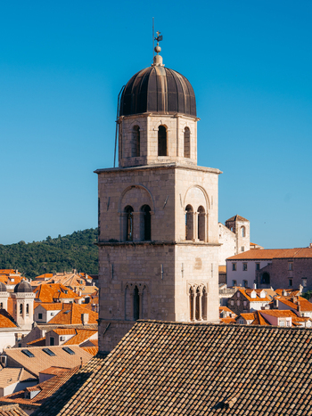 View of the historic stone bell tower rising above the orange tiled rooftops of the old town under a clear blue sky in Dubrovnik Dubrovnik Neretva County Croatia. View of the historic stone bell tower rising above the orange tiled rooftops of the old town under a clear blue sky in Dubrovnik Dubrovnik Neretva County Croatia.
