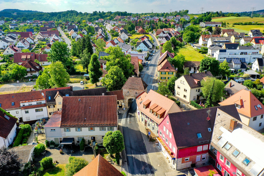 Aerial view of the historic town center featuring traditional red tiled roofs lush green trees and a medieval stone gate tower Neunkirchen am Brand Bavaria Germany. Aerial view of the historic town center featuring traditional red tiled roofs lush green trees and a medieval stone gate tower Neunkirchen am Brand Bavaria Germany.