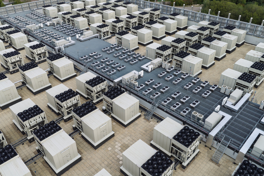 Aerial view of a data center rooftop featuring numerous industrial HVAC cooling units and ventilation systems arranged in rows United Kingdom.