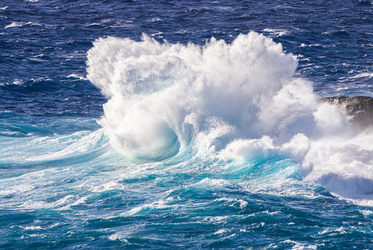 View of a powerful ocean wave crashing against the rocky coastline of the North Shore in Haleiwa Hawaii United States.