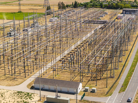Aerial view of Amprion Umspannwerk electrical substation with metal structures power lines and transformers in the rural landscape of Pfungstadt Hessen Germany.