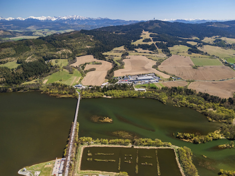 Aerial view of Oravska priehrada reservoir with a long bridge surrounding green hills and snow capped Tatra mountains in the distance Namestovo Zilinsky kraj Slovakia. Aerial view of Oravska priehrada reservoir with a long bridge surrounding green hills and snow capped Tatra mountains in the distance Namestovo Zilinsky kraj Slovakia.