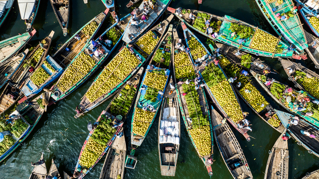 Rangamati Bangladesh 19 October 2022 Aerial view of wooden boats heavily loaded with coconuts on the water with people working and sorting the fruit.