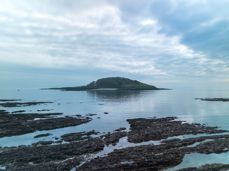 Aerial view of Looe Island surrounded by calm sea and rocky shoreline under a cloudy sky in Looe Cornwall United Kingdom. Aerial view of Looe Island surrounded by calm sea and rocky shoreline under a cloudy sky in Looe Cornwall United Kingdom.