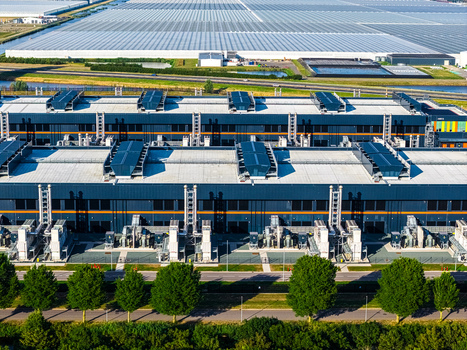 Aerial view of Agriport A7 industrial facility featuring extensive rooftop cooling infrastructure and large adjacent greenhouse complexes in Middenmeer Noord Holland Netherlands. Aerial view of Agriport A7 industrial facility featuring extensive rooftop cooling infrastructure and large adjacent greenhouse complexes in Middenmeer Noord Holland Netherlands.