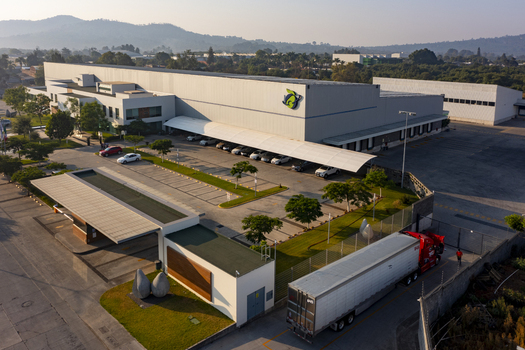 Aerial view of an avocado packing house exterior featuring a large industrial facility parking lot with vehicles and a semi truck parked in Uruapan Michoacan Mexico.