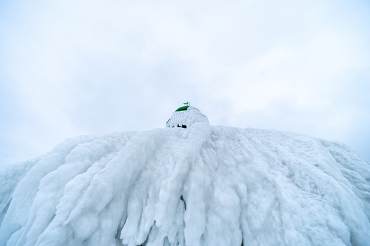 View of Molenfeuer Sassnitz lighthouse completely covered in thick layers of ice and icicles during a cold winter day in Sassnitz Mecklenburg Vorpommern Germany.