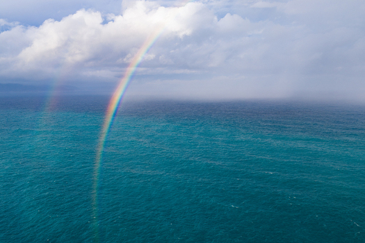 Aerial view of a vibrant rainbow arching over the turquoise waters of the Southern Ocean at Two Peoples Bay Nature Reserve with dramatic clouds in Albany Western Australia Australia.