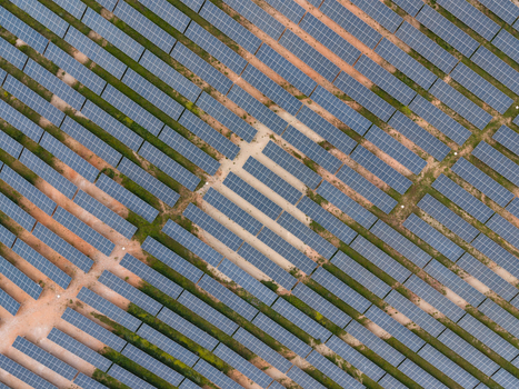 Aerial view of solar panels arranged in rows with dirt paths in Italy.