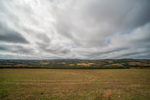 View of the rolling countryside and agricultural fields under a cloudy sky in Fowey Cornwall United Kingdom. View of the rolling countryside and agricultural fields under a cloudy sky in Fowey Cornwall United Kingdom.