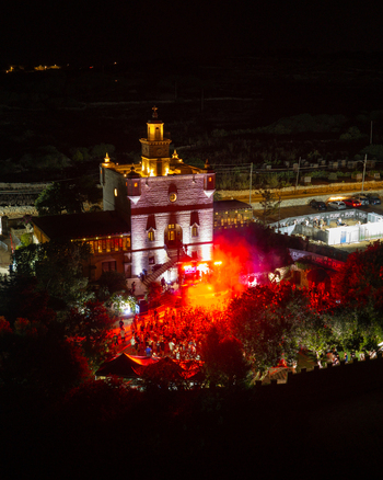Mgarr Malta 17 September 2026 Aerial view of Castello Zamittello illuminated at night during an outdoor event with a crowd of people and vibrant red stage lighting. Mgarr Malta 17 September 2026 Aerial view of Castello Zamittello illuminated at night during an outdoor event with a crowd of people and vibrant red stage lighting.