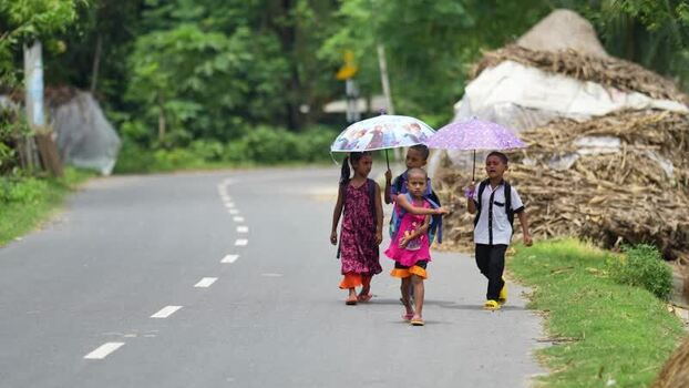 View of school children walking with umbrellas on a road Bangladesh.