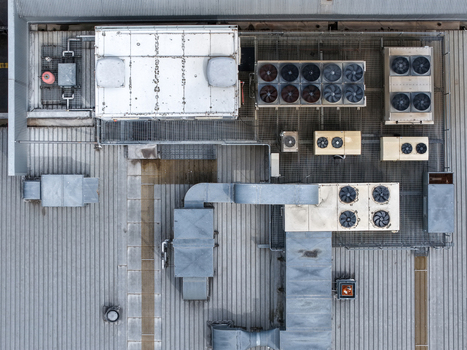 Aerial view of an industrial rooftop featuring various HVAC systems ventilation ducts and cooling fans arranged on a metal surface in Melbourne VIC Australia.
