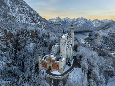 Aerial view of Neuschwanstein Castle s spires piercing the snow laden landscape under a pastel sky a fairy tale frozen in time Schwangau Bayern Germany.