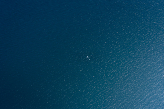 Aerial view of a small boat floating in the deep blue waters of the ocean Shire of Shark Bay Western Australia Australia. Aerial view of a small boat floating in the deep blue waters of the ocean Shire of Shark Bay Western Australia Australia.