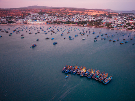 Aerial view of numerous fishing boats anchored in a bay near a coastal town in Vietnam. Aerial view of numerous fishing boats anchored in a bay near a coastal town in Vietnam.
