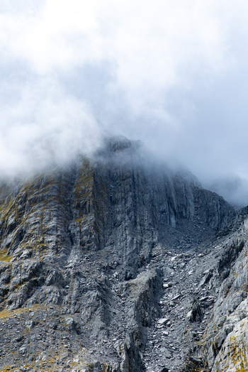 View of a rugged mountain range shrouded in ethereal mist with textured rocks and sparse vegetation showcasing nature s grandeur Franz Josef West Coast Region New Zealand. View of a rugged mountain range shrouded in ethereal mist with textured rocks and sparse vegetation showcasing nature s grandeur Franz Josef West Coast Region New Zealand.