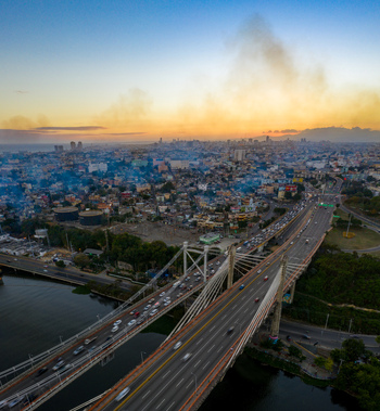 Aerial view of the Juan Bosch Bridge spanning the Ozama River with heavy traffic and the urban skyline of Santo Domingo at sunset Santo Domingo Distrito Nacional Dominican Republic. Aerial view of the Juan Bosch Bridge spanning the Ozama River with heavy traffic and the urban skyline of Santo Domingo at sunset Santo Domingo Distrito Nacional Dominican Republic.
