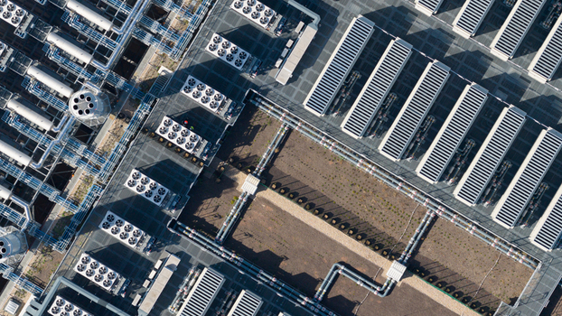 Aerial view of an industrial facility featuring rows of cooling fans HVAC units and complex piping systems on the roof in Dietzenbach Hessen Germany. Aerial view of an industrial facility featuring rows of cooling fans HVAC units and complex piping systems on the roof in Dietzenbach Hessen Germany.