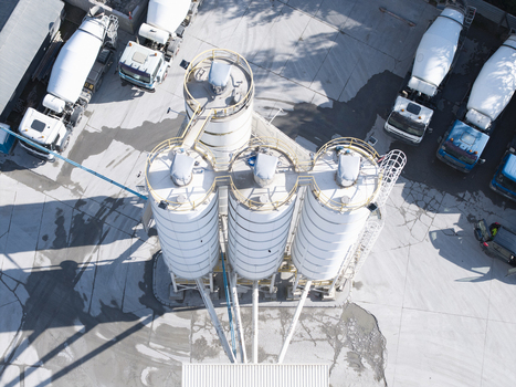 Aerial view of the Holcim concrete plant featuring industrial silos and parked cement mixer trucks on a paved yard in Krakow Lesser Poland Voivode Poland.