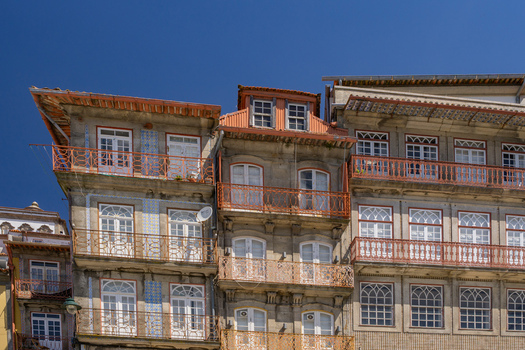Aerial view of aged buildings with weathered stone facades and ornate balconies under a vibrant blue sky Porto Porto District Portugal. Aerial view of aged buildings with weathered stone facades and ornate balconies under a vibrant blue sky Porto Porto District Portugal.