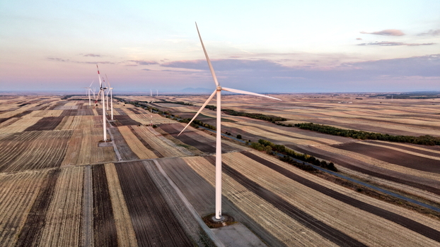 Aerial view of wind turbines standing in vast agricultural fields during golden hour in Vladimirovac Vojvodina Serbia.