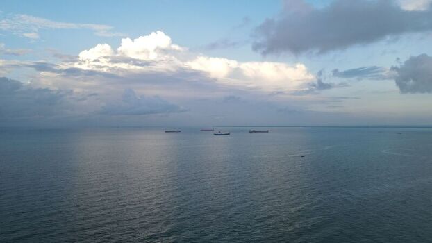 Aerial view of cargo ships anchored in the calm waters off the coast under a cloudy sky in Balikpapan East Kalimantan Indonesia. Aerial view of cargo ships anchored in the calm waters off the coast under a cloudy sky in Balikpapan East Kalimantan Indonesia.