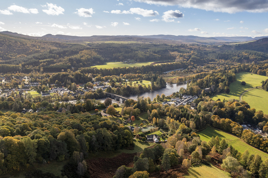 Aerial view of Dunkeld Bridge crossing the River Tay surrounded by vibrant autumn forests and rolling hills in Dunkeld Scotland United Kingdom. Aerial view of Dunkeld Bridge crossing the River Tay surrounded by vibrant autumn forests and rolling hills in Dunkeld Scotland United Kingdom.
