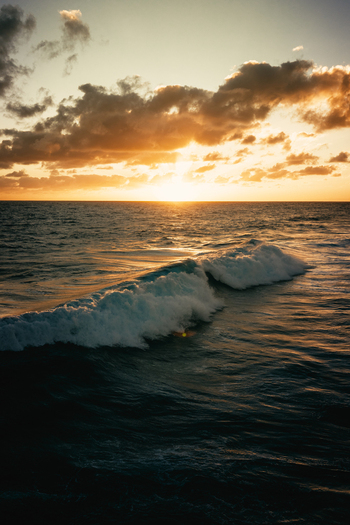 Aerial view of ocean waves breaking at sunset with golden light reflecting on the water near Rarotonga Cook Islands. Aerial view of ocean waves breaking at sunset with golden light reflecting on the water near Rarotonga Cook Islands.